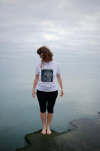 MIXMON – woman by the water, seen from behind, wearing the colour-inverted BRAIN SCAN design on a white tee – MIXIGNALS by Alex Beriault